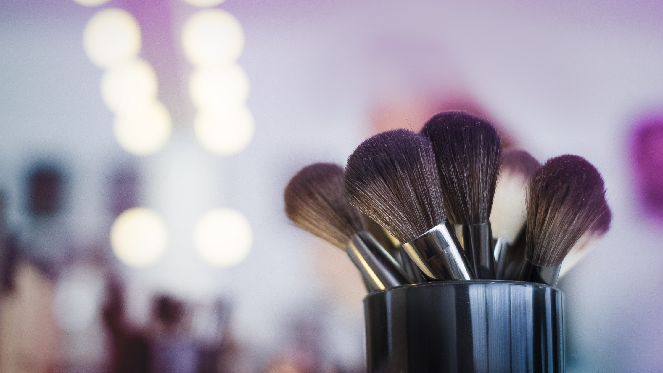 Close-up of makeup brushes in front of a blurred background.