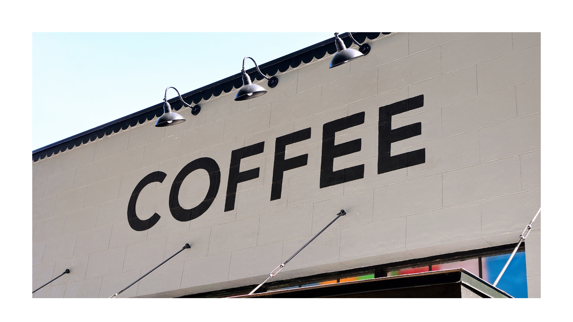 Sign with black letters on a white building that reads "COFFEE"