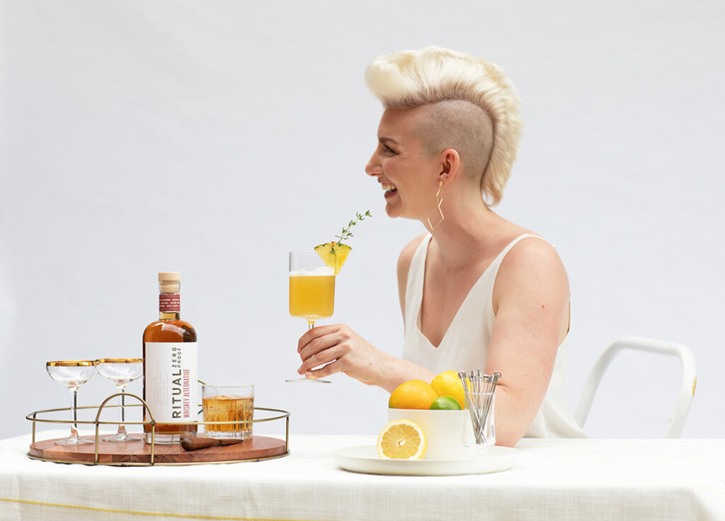 Gen-Z individual with a blond mowhawk drinking a hand-crafted mocktail with Ritual, a premium non-alcoholic beverage.